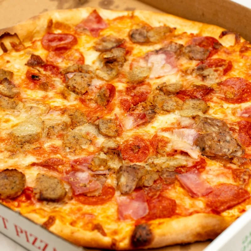 A meat lovers pizza with pepperoni, sausage, meatball and ham in a Bella Italia pizza box